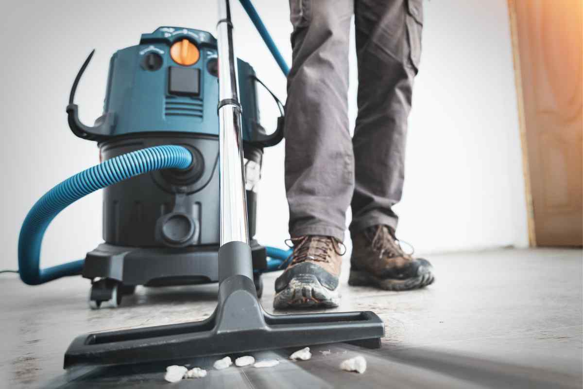Worker vacuuming floor debris with shop vacuum