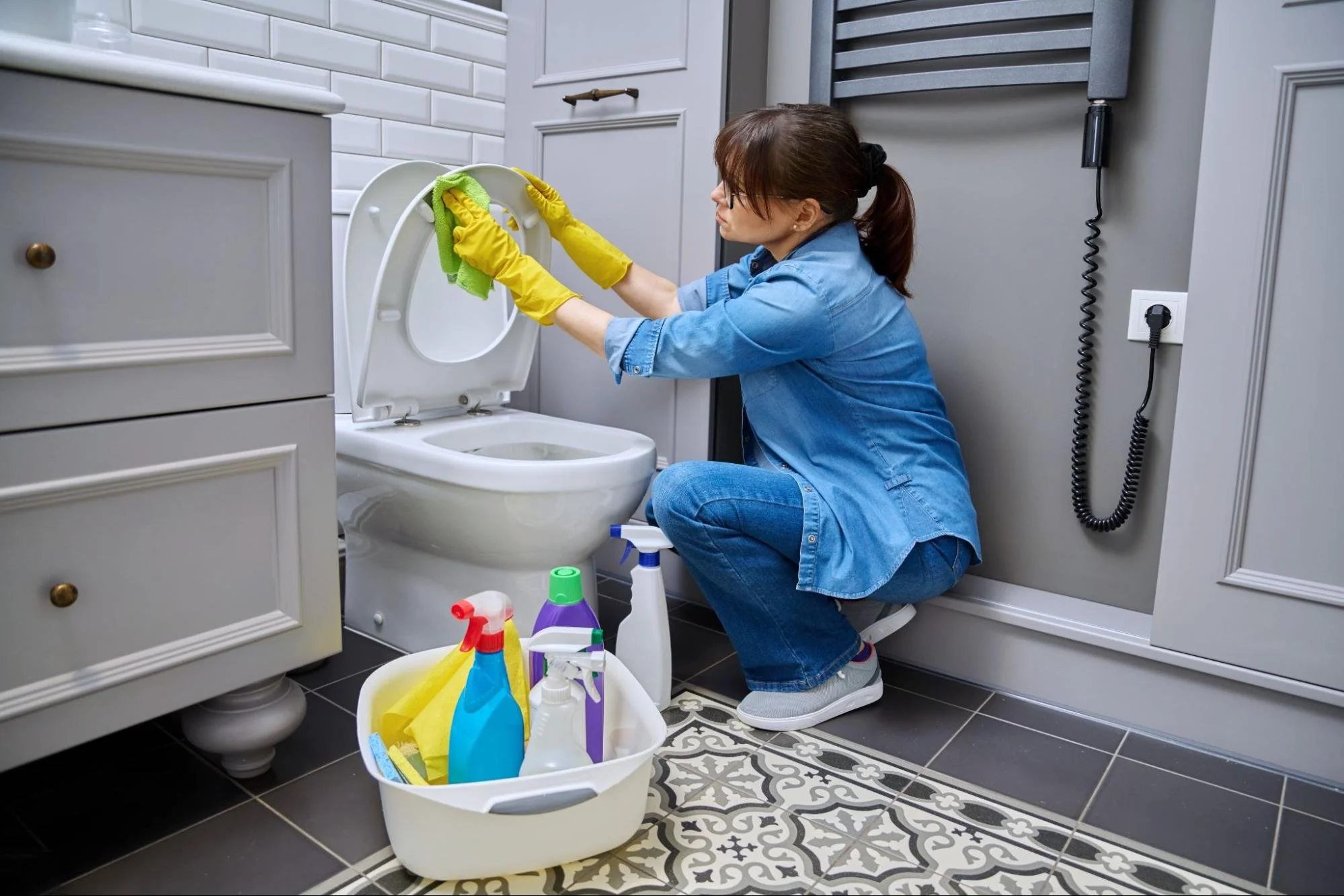Woman cleaning toilet wearing yellow rubber gloves